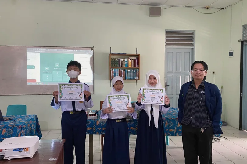 William and students holding certificates in a classroom.