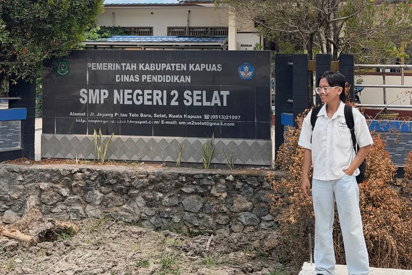 William standing beside the SMP Negeri 2 Selat sign.