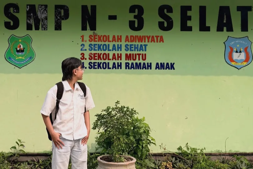 William standing in front of the SMPN 3 Selat sign.